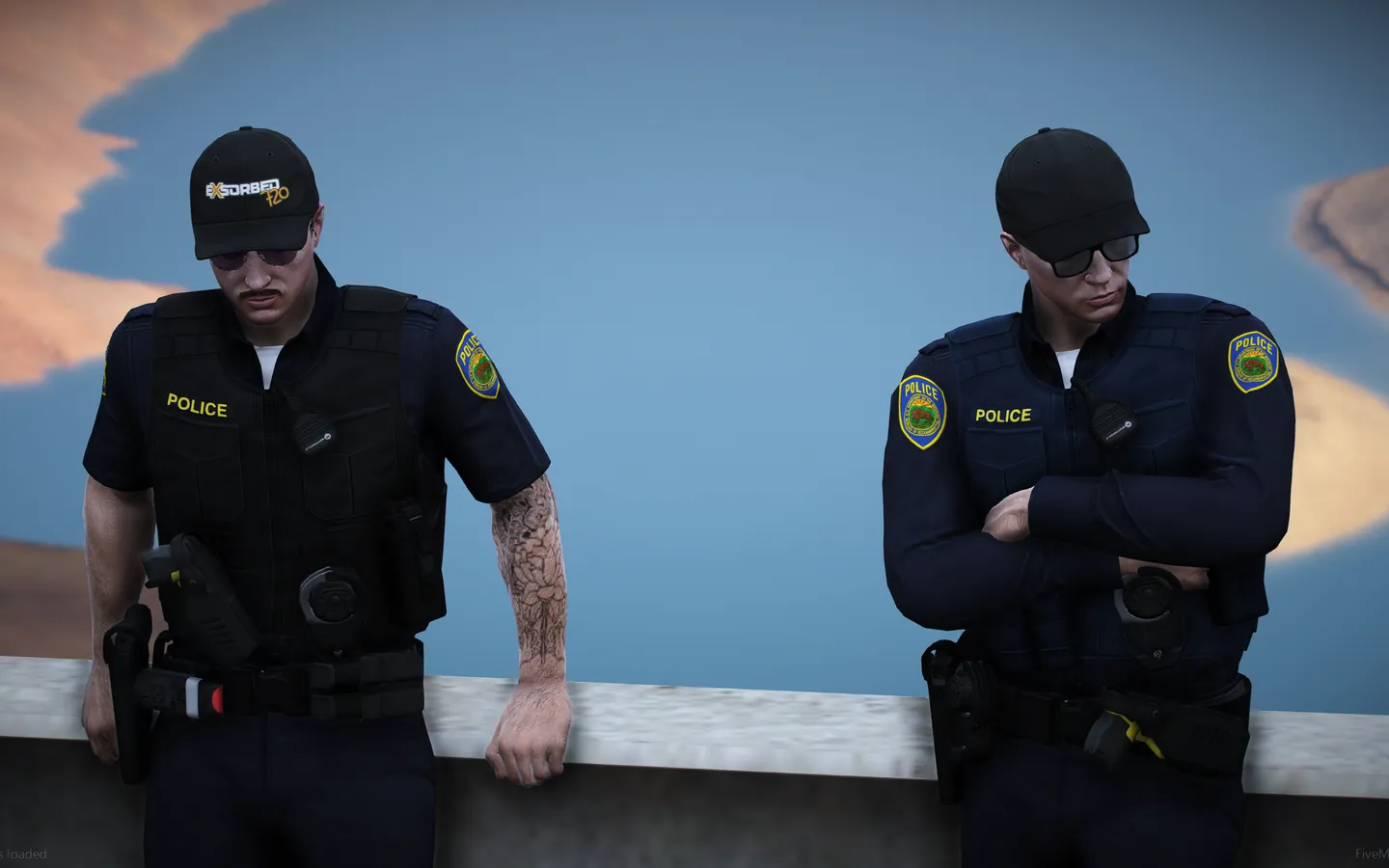 Two officers leaning on a wall by the water