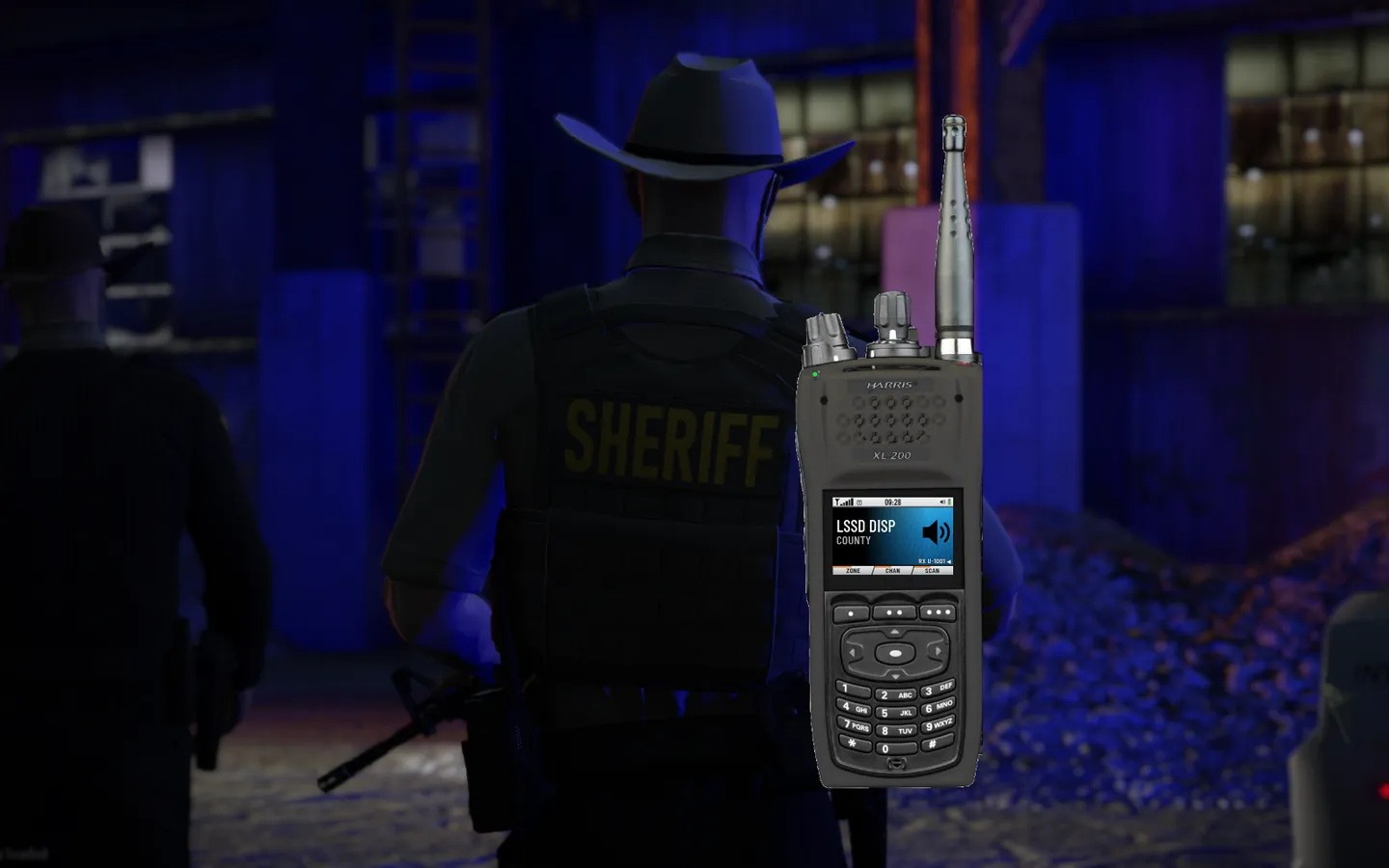 A Flaming Radio handheld showing the LSSD dispatch talkgroup, beside a sheriff's deputy at night